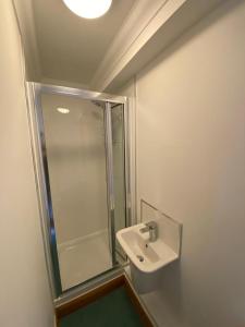 a white bathroom with a shower and a sink at Stylish & compact city center studio apartment in Norwich