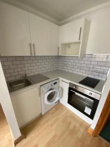 a kitchen with a sink and a washing machine at Stylish & compact city center studio apartment in Norwich