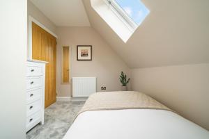 a bedroom with a white bed and a skylight at Robins Nest Cottage in Blairgowrie