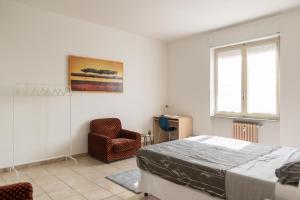 una camera con un letto e una sedia e una finestra di [House of Poet] Wide Apartment in the City Center ad Asti