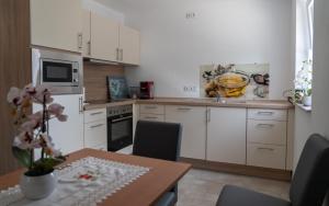 a kitchen with white cabinets and a table with chairs at Ferienwohnung mit Salzachblick in Laufen