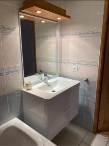 y baño con lavabo blanco y espejo. en Les Granges 15, en Montalbert