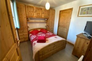 1 dormitorio con 1 cama con almohadas rojas y TV en Les Granges 15, en Montalbert