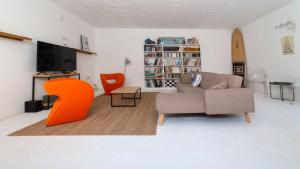 ein Wohnzimmer mit einem Sofa und einem orangenen Stuhl in der Unterkunft KEFI SPITIA in Simotáta