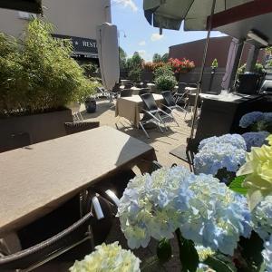 un patio con tavoli, sedie e fiori blu di Hôtel de Guise SARL a Guise