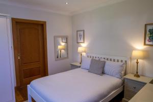ein Schlafzimmer mit einem weißen Bett mit blauen Kissen in der Unterkunft Glenview Luss in Luss