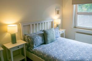 a bedroom with a bed with blue pillows and two lamps at Glenview Luss in Luss
