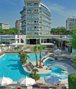 a swimming pool with umbrellas and a large building at Majestic Beach Hotel & Wellness in Bibione
