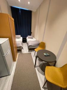 Habitación con 2 camas, mesa y nevera. en Kuukkeli Ivalo Airport Inn, en Ivalo