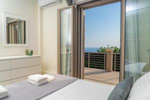 a bedroom with a bed and a balcony with the ocean at Lourdas Bay View in Kefallonia