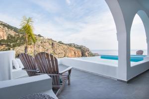 Duas cadeiras e uma mesa numa varanda com vista para o oceano em Vento Isolano suites em Cárpatos