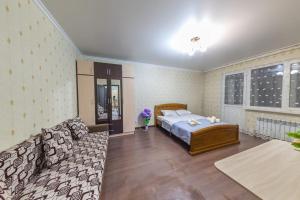 1 dormitorio con 1 cama y 1 sofá en Просторная квартира в жк Науаи около ТРЦ МЕГА, en Almaty