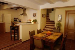 a dining room with a table and a kitchen with a staircase at Casa Antonio in Alájar