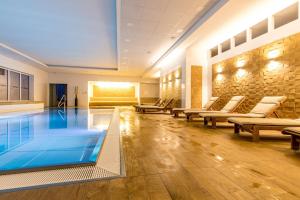 a pool in a building with lounge chairs and tables at Spa Moser apartments in Karlovy Vary