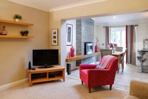 - un salon avec une télévision et une chaise rouge dans l'établissement Stylish family home in desirable Penylan + Parking, à Cardiff