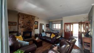 a living room with leather furniture and a stone fireplace at Ambassador Lodge in Dullstroom