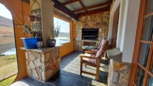 a porch with a stone fireplace and a chair at Ambassador Lodge in Dullstroom