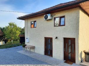 a house with two doors and a bench in front of it at Begova kuća-Velika Kladuša in Velika Kladuša