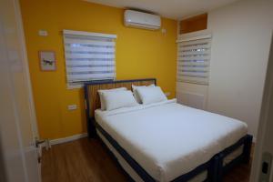 a bedroom with a white bed with a yellow wall at RAKEFET - Traveler's House - EILAT in Eilat
