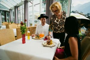 Una donna in piedi a un tavolo con un uomo che mangia cibo di Gailtaler Hof a Kötschach-Mauthen