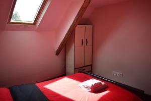 Un dormitorio con una cama con sábanas rojas y una ventana en Le Noble Jardin, en Mohon