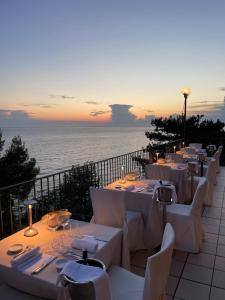 a restaurant with white tables and chairs and the ocean at Hotel Riviera & Maximilian's in Trieste