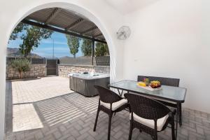 un patio con tavolo, sedie e griglia di Kimia Luxury Apartments a Kolímbia