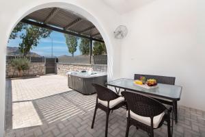 eine Terrasse mit einem Tisch, Stühlen und einem Grill in der Unterkunft Kimia Luxury Apartments in Kolymbia