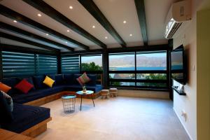 RAKEFET - Traveler's House - EILAT في إيلات: غرفة معيشة مع أريكة زرقاء ونوافذ كبيرة