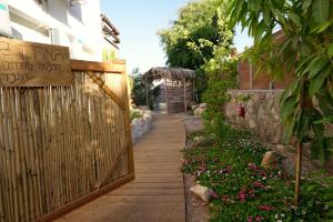 Una pasarela en un jardín con una valla y flores en RAKEFET - Traveler's House - EILAT, en Eilat