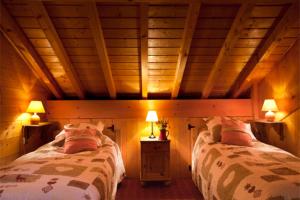 two beds in a room with wooden walls and ceilings at Chalet Juliet 10 people in Montalbert