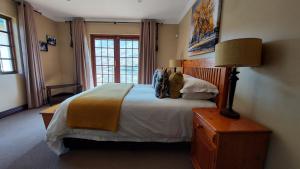 a bedroom with a large bed and a lamp at Aviemore Lodge in Dullstroom