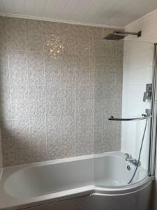 a bath tub in a bathroom with a tiled wall at Sea Breeze is next to the Beach & Harbour in Harwich