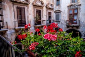 una olla de flores rojas delante de un edificio en Ballaro' Hotel - Budget Room, en Palermo