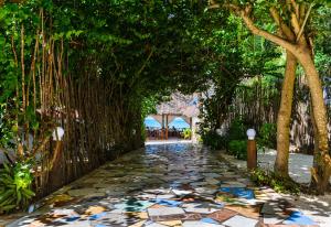 une passerelle avec des arbres et un chemin en pierre dans l'établissement Geo Zanzibar Resort, à Jambiani