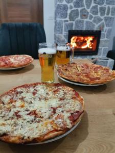 two pizzas on a table with two glasses of beer at Villa Grkasha in Ohrid