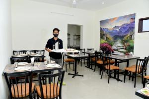 a man with a mask in a restaurant with tables at The Divine Oak Golden Leaf in Katra