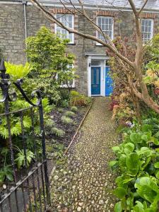 a pathway leading to a house with a blue door at Fuchsia Cottage in Flushing