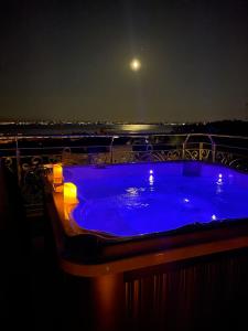 una vasca idromassaggio blu su un balcone di notte di BELLAVISTA EXCLUSIVE B&B VISTA LAGO Piscina riscaldata e Jacuzzi a Desenzano del Garda