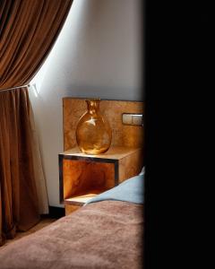 فندق مونوبول في كاتوفيسي: وجود مزهرية تجلس على موقف ليلي بجانب سرير