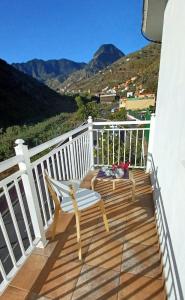 a wooden balcony with a chair and a view of mountains at Casa Efraim in Hermigua