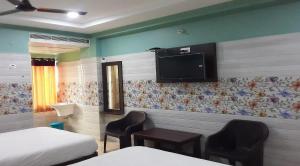 a room with two beds and a tv on the wall at Surya Grand Tiruchanoor Tirupati in Tirupati