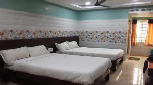 a bedroom with two beds and a wall with at Surya Grand Tiruchanoor Tirupati in Tirupati