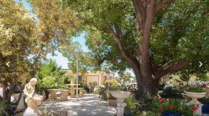 a garden with a statue and flowers and a tree at Sturt Motel Balranald in Balranald