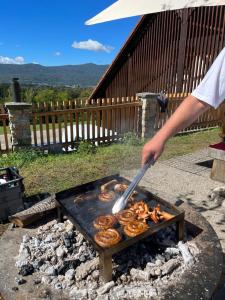 uma pessoa está cozinhando comida em uma grelha em Zidanica Malerič em Dragatuš