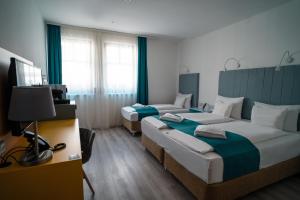 una camera d'albergo con due letti e una televisione di Hotel Civitas a Sopron