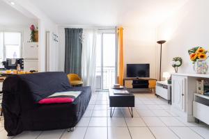 a living room with a black couch and a tv at Le Clos des Rosiers in Toulouse