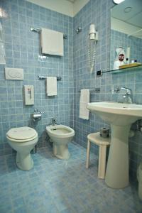 bagno piastrellato blu con servizi igienici e lavandino di Sam Hotel a Monfalcone