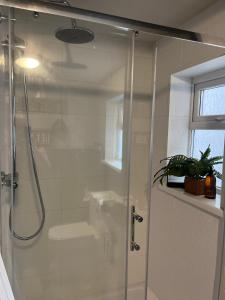 una ducha con puerta de cristal en un baño en CWTCH COTTAGE Llantrisant 2 bed home - sleeps 4, en Llantrisant