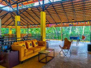 sala de estar con sofá amarillo y sillas en The Hosteller Coorg Rainforest, Madikeri, en Madikeri